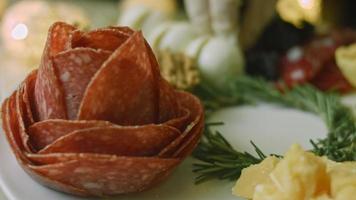 charkuterivaror tallrik med salami, annorlunda typer av ost. den har torkades frukter, olika nötter och honung. Semester arrangemang med brinnande ljus video