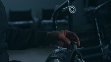 Side view of one American male workers in a workshop at a factory making wheelchairs, sitting at a workbench using hand tools and assembling parts of a product, sitting in wheelchairs video