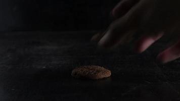 stack of chocolate cookies on wooden table on black background video