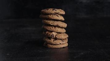 pile de biscuits au chocolat sur une table en bois sur fond noir video