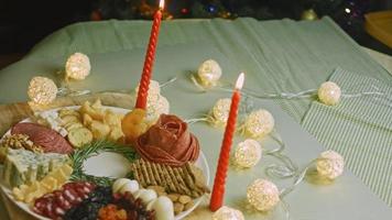 Charcuterie plate with salami, different kinds of cheese. It has dried fruits, various nuts and honey. Holiday arrangement with burning candles video