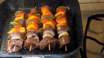 kebabs de ternera marinada con verduras preparadas a la parrilla. el cocinero voltea la carne para freír en otro lugar
