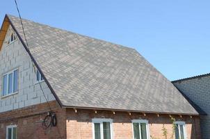 Flexible shingles of bitumen roofing surface on the brick house photo