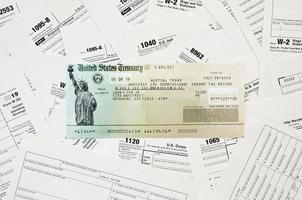 Refund check on many tax form blanks lies on table close up. Tax payers paperwork routine and bureaucracy concept photo