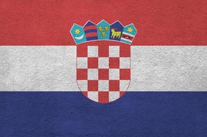 Croatia flag depicted in bright paint colors on old relief plastering wall. Textured banner on rough background photo