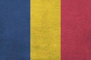 Chad flag depicted in bright paint colors on old relief plastering wall. Textured banner on rough background photo