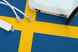 Sweden flag depicted on table with internet rj45 cable, wireless usb wifi adapter and router. Internet connection concept photo