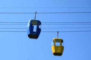 cabinas de teleférico de pasajeros azules y amarillas en el cielo despejado foto
