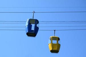 Blue and yellow passenger cable way cabins in the clear sky photo