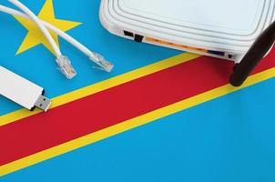 Democratic Republic of the Congo flag depicted on table with internet rj45 cable, wireless usb wifi adapter and router. Internet connection concept photo