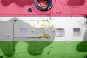 Tajikistan flag depicted on side part of military armored helicopter closeup. Army forces aircraft conceptual background photo
