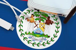 Belize flag depicted on table with internet rj45 cable, wireless usb wifi adapter and router. Internet connection concept photo