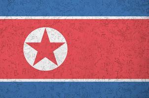 North Korea flag depicted in bright paint colors on old relief plastering wall. Textured banner on rough background photo