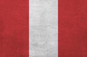Peru flag depicted in bright paint colors on old relief plastering wall. Textured banner on rough background photo