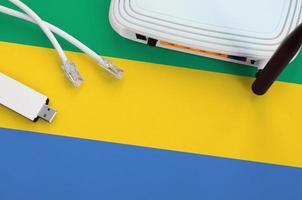 Gabon flag depicted on table with internet rj45 cable, wireless usb wifi adapter and router. Internet connection concept photo