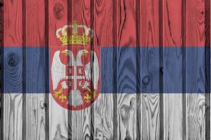 bandera serbia representada en colores de pintura brillante en una pared de madera vieja. banner texturizado sobre fondo áspero foto