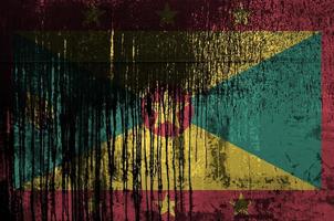 Grenada flag depicted in paint colors on old and dirty oil barrel wall closeup. Textured banner on rough background photo