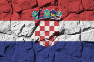 bandera de croacia representada en colores de pintura en el primer plano de la pared de piedra antigua. banner texturizado sobre fondo de pared de roca foto
