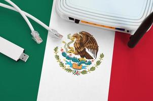 bandera de méxico representada en la mesa con cable de internet rj45, adaptador wifi usb inalámbrico y enrutador. concepto de conexión a internet foto