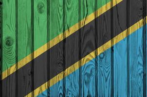 Tanzania flag depicted in bright paint colors on old wooden wall. Textured banner on rough background photo