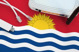 Kiribati flag depicted on table with internet rj45 cable, wireless usb wifi adapter and router. Internet connection concept photo