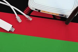 Malawi flag depicted on table with internet rj45 cable, wireless usb wifi adapter and router. Internet connection concept photo