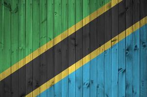 Tanzania flag depicted in bright paint colors on old wooden wall. Textured banner on rough background photo