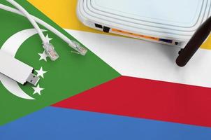 Comoros flag depicted on table with internet rj45 cable, wireless usb wifi adapter and router. Internet connection concept photo