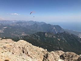 Paragliding in mountains. Freedom to fly in air over mountains with parachute. Paragliding behind blue sky Carpathian Mountains hills range landscape. Active tourist sport People fly using Parachute photo