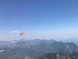 Skydiver with a dark blue canopy on the background a blue sky above clouds photo