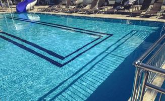 Swimming pool at the hotel next to the entrance. blue chlorinated water, at the bottom of the pool - tiles and a blue pattern photo