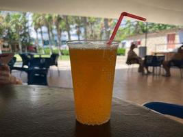 Fresh orange juice in the glass on a wooden table against the natural bokeh background photo