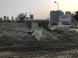 suciedad en un sitio de construcción. surcos de arena, huellas de vehículos pesados. cerca se encuentran materiales de construcción, piezas de hormigón y otros bloques de construcción, residuos de construcción, contaminación ambiental foto