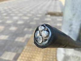 A close-up view of a thick cross-sectional industrial aluminum cable in black rubber insulation photo