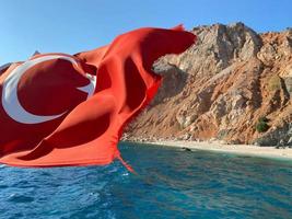 Turkish flag on the background of the mountains in Kemer, in the background the sea, sunny day, horizontal frame photo
