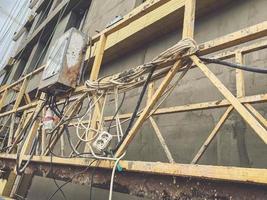 metal structure at the construction site. wires and extensions were hung on a yellow metal fence. a cabinet with power lines hangs on the structure photo