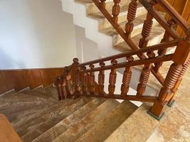 Luxury interior marble staircase with wrought iron railing and wooden handrail photo