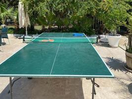 tennis table in the park with a playground in the background on a sunny day photo