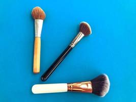 three brushes on a light blue background. natural bristle brushes for applying loose and liquid cosmetics to the skin of the face. makeup artist tool, creating perfect skin photo