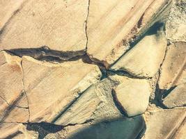 broken road made of natural stone. beige color texture, natural material. concrete slabs with cracks, broken road photo