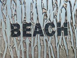 Old cracked inscription Beach in large letters on the plate. A brutal beach vacation concept photo