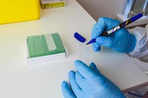 Cropped image of scientist holding microscope slide over box at laboratory photo