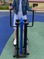 una mujer practica deportes en un nuevo y moderno entrenador de piernas azul para caminar y correr en un sitio de entrenamiento al aire libre foto