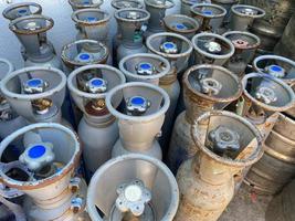 muchos cilindros de oxígeno y cilindros de argón con gas comprimido asegurados en el almacén de la fábrica de gas. tanques de oxígeno verdes para el hospital. tanques de oxigeno negros para la industria. tanques de argon azul para la industria foto