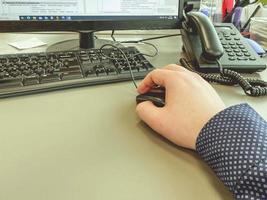 office work. a man in a blue shirt clicks on a mouse. work at the computer. intellectual work. the programmer composes the code for the site photo