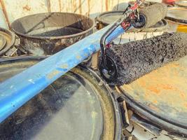 construction site. on the ground are barrels of paint and resin. black resin is spilled from the barrel. on the barrels lies a blue heavy beam and a paint roller photo