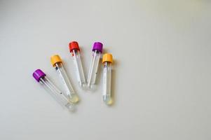 cinco tubos de ensayo con tapas multicolores sobre un fondo blanco. tubos de ensayo para diagnósticos de salud, donación de sangre de una vena. laboratorio, análisis, indicadores para evaluar el estado de salud foto