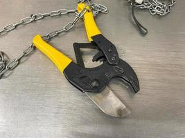 Large iron sharp metal scissors, metal cutters with chains, lie on an iron table. Hand-held locksmith tools. The background photo