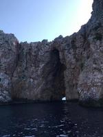 entrada o abertura de un agujero de piedra en la pared de una cueva de roca mirando al cielo y al mar foto