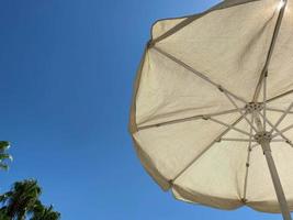 Looking up at a parasol against a blue sky, on a warm day photo